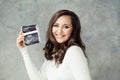 Pregnant woman holding ultrasound scan image and smiling Royalty Free Stock Photo