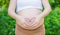 Pregnant woman holds belly heart. Selective focus