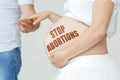 A pregnant woman holds her husband's hand on her stomach with the inscription - STOP ABORTIONS Royalty Free Stock Photo