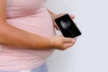 pregnant woman holds mobile phone with ultrasound screen examination