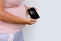 Pregnant woman holds mobile phone with ultrasound screen examination, small child rolls over in mother`s belly, concept pregnancy