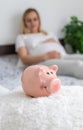 A pregnant woman holds a pig bank in her hands. Selective focus Royalty Free Stock Photo