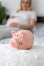 A pregnant woman holds a pig bank in her hands. Selective focus Royalty Free Stock Photo