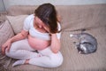 Pregnant woman holds on to a sore head in home interior, lifestyle