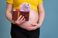 Pregnant woman holds a wallet with money and credit cards