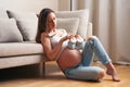 Pregnant woman at home holding small baby shoes Royalty Free Stock Photo