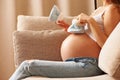 Pregnant woman at home holding small baby shoes Royalty Free Stock Photo