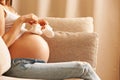 Pregnant woman at home holding small baby shoes Royalty Free Stock Photo