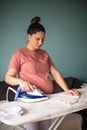 Pregnant woman at home ironing baby laundry Royalty Free Stock Photo