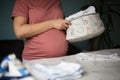 Pregnant woman at home preparing baby laundry