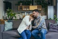 Pregnant woman at home sitting on sofa sad and crying, husband calms and supports, young married couple Royalty Free Stock Photo