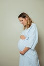 Pregnant woman in hospital robe hold big belly profile view Royalty Free Stock Photo