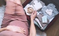 Pregnant woman hugging belly and packing maternity hospital bag. Beautiful mother during pregnancy waiting for baby preparing Royalty Free Stock Photo