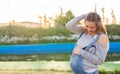 Pregnant woman hugging her belly outdoors
