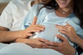 Pregnant woman with husband in bedroom with the atmosphere of having fun talking