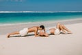 Pregnant woman with husband expecting baby kiss at tropical beach with blue sea Royalty Free Stock Photo