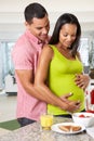 Pregnant Woman And Husband Having Breakfast In Kitchen