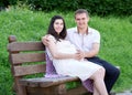 Pregnant woman and husband on outdoor, happy family, couple in city park, summer season, green grass and trees Royalty Free Stock Photo