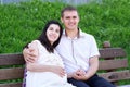 Pregnant woman and husband on outdoor, happy family, couple in city park, summer season, green grass and trees Royalty Free Stock Photo