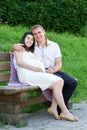 Pregnant woman and husband on outdoor, happy family, couple in city park, summer season, green grass and trees Royalty Free Stock Photo