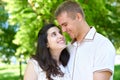 Pregnant woman with husband posing in the city park, family portrait, summer season, green grass and trees Royalty Free Stock Photo