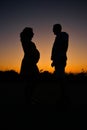 Pregnant woman and husband sihouettes in sunset