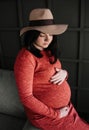 Pregnant woman inside room gently strokes belly