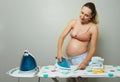 Pregnant woman with iron at home prepare baby clothes Royalty Free Stock Photo