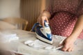Pregnant woman ironing baby laundry at home Royalty Free Stock Photo