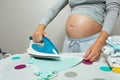 Close-up of a pregnant woman ironing newborn baby clothes Royalty Free Stock Photo