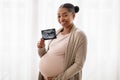 Pregnant woman keeping hand on belly and holding ultrasound image Royalty Free Stock Photo