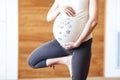 A pregnant woman keeps her balance, practicing yoga. Close-up of the belly