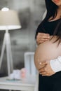 A pregnant woman keeps her hands on her stomach, supporting her unborn child