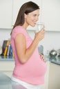 Pregnant woman in kitchen with glass of water Royalty Free Stock Photo