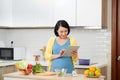 Pregnant woman on kitchen making healthy salad with digital tablet Royalty Free Stock Photo