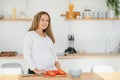 Pregnant woman in kitchen making salad Royalty Free Stock Photo