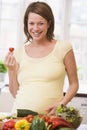 Pregnant woman in kitchen making a salad smiling Royalty Free Stock Photo
