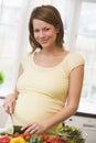 Pregnant woman in kitchen making a salad smiling Royalty Free Stock Photo