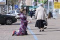 Pregnant woman kneeling on a pavement and begging