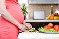 Pregnant woman with knife on kitchen cuts cucumber Royalty Free Stock Photo