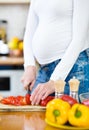 Pregnant woman with knife on kitchen cuts vegetables Royalty Free Stock Photo