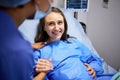 Pregnant woman, labor and hospital with holding hands, bed and support from nurse, excited smile and pain. Strong mother