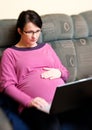Pregnant woman with laptop in bed Royalty Free Stock Photo