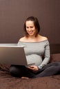 Pregnant woman with laptop sitting on bed Royalty Free Stock Photo