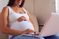 Pregnant woman with laptop sitting on sofa at home Royalty Free Stock Photo