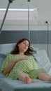 Pregnant woman laying in hospital ward bed waiting on assistance Royalty Free Stock Photo