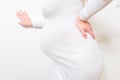 Pregnant woman leaning on edge of bed and touching her painful back. Body health problem in pregnancy time. Close up. Side view Royalty Free Stock Photo