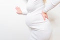 Pregnant woman leaning on edge of bed and touching her painful back. Body health problem in pregnancy time. Close up. Side view Royalty Free Stock Photo