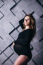 A pregnant woman in lingerie with a big belly in the ninth month of pregnancy is posing next to a big five-pointed star. in Royalty Free Stock Photo