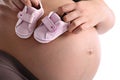 Pregnant woman with little baby shoes on her belly Royalty Free Stock Photo